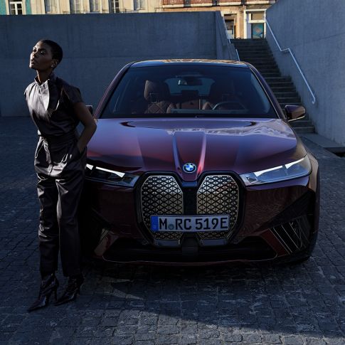 BMW iX front view with model BMW iX Aventurin Red i20 front view with model
