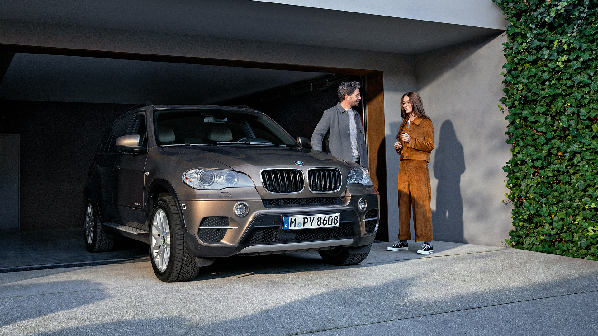 BMW Value Service man and woman in front of garage with BMW X5 BMW Value Service man and woman in front of garage with BMW X5